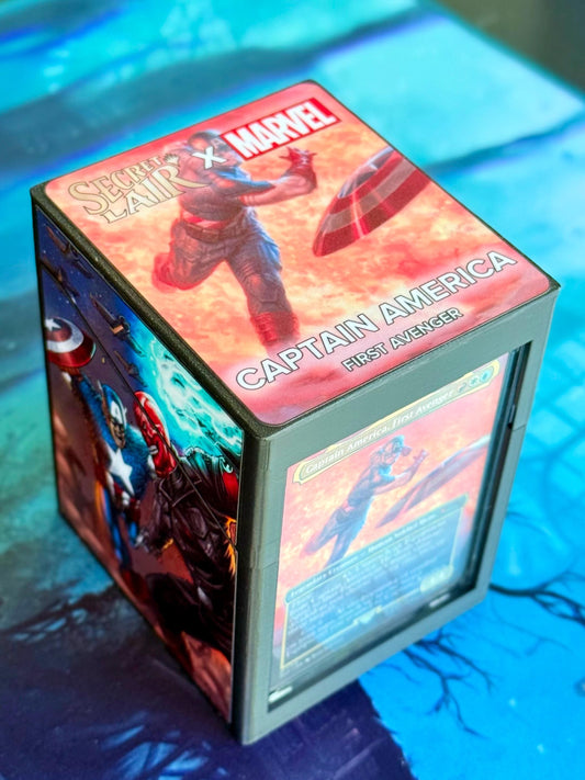 May include: A black and gray card deck box with a Secret Lair x Marvel Captain America: First Avenger design. The box features a red, orange, and blue illustration of Captain America throwing his shield. The text 'Secret Lair x Marvel' and 'Captain America: First Avenger' is printed on the box.