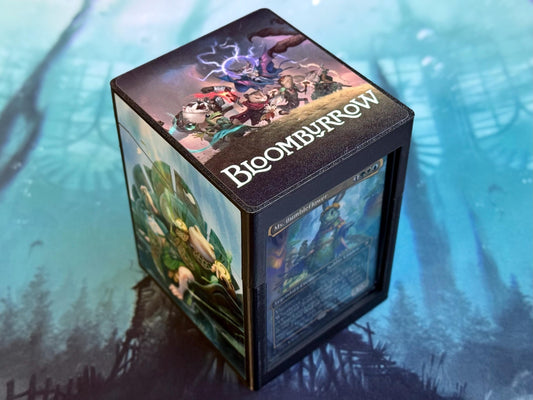 May include: Black deck box for trading cards.  Features a vibrant full-color wrap-around design showcasing fantasy characters and a stormy landscape.  The top displays the name 'BLOOMBURROW' in white lettering.  The box includes a clear window to display a card inside.  A Magic: The Gathering card is partially visible through the window.