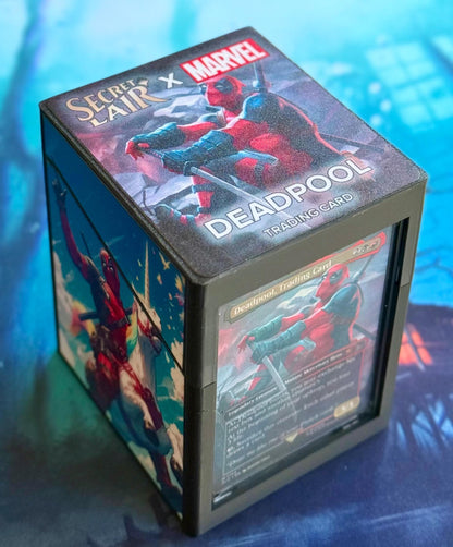May include: A black and gray card deck box with a Secret Lair x Marvel Deadpool trading card design. The box features a red and black Deadpool character on the top and a Deadpool trading card on the side.